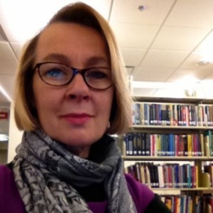 Blonde haired caucasian woman in purple scarf in front of books