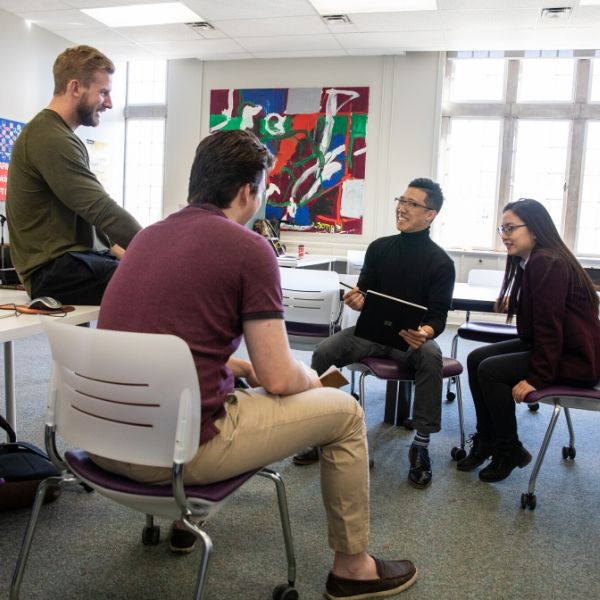 Image displays 4 student entrepreneurs sitting around, in a circle brainstorming ideas. 
