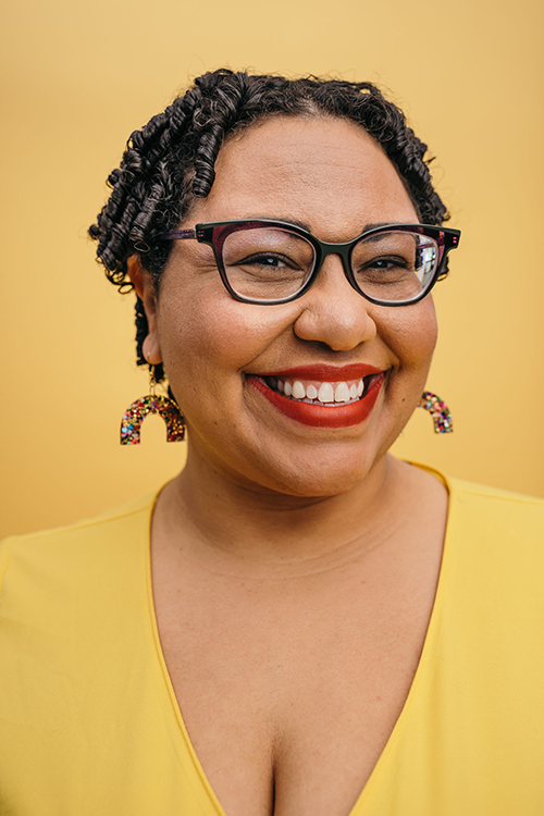 Headshot of Sami Schalk in a yellow shirt on a yellow background.