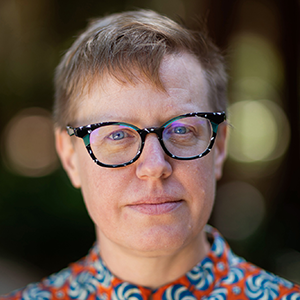Headshot of Emily Drabinski in a patterned shirt with dark-rimmed glasses on.