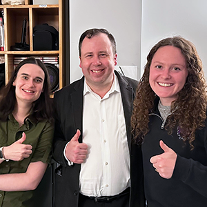 Meghan Voll, Mark Ambrogio and Amalie Hutchinson group photo with their thumbs up.