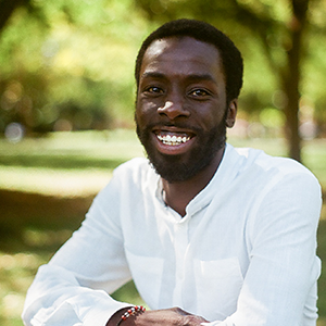 Desmond Cole in a white shirt sitting outside in the summer.