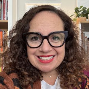 Headshot of Dr. Amanda Cachia who has curly hair and is wearing glasses.