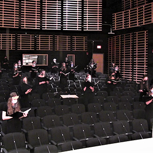 Choir members singing in face masks, shields in von Kuster Hall