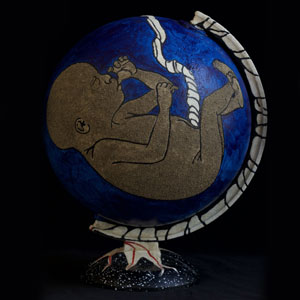 A globe is painted blue with a fetus sucking it's thumb